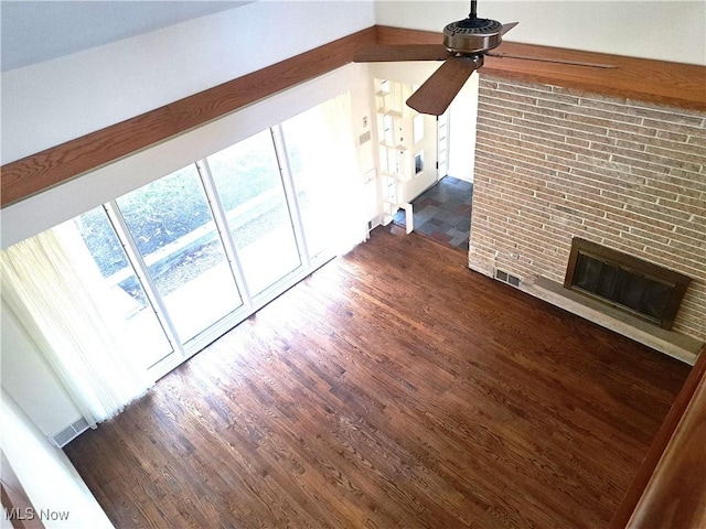 unfurnished living room featuring dark wood-type flooring, a brick fireplace, a ceiling fan, and visible vents