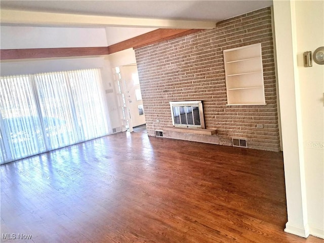 unfurnished living room featuring visible vents, beamed ceiling, a brick fireplace, and wood finished floors