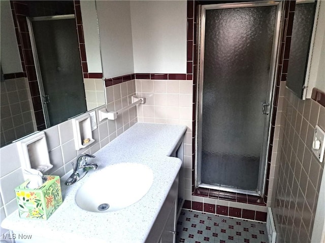 bathroom with tile walls, a stall shower, and vanity