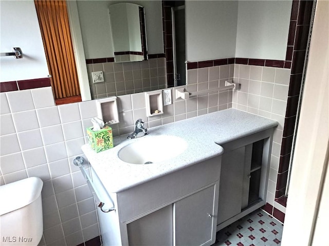 bathroom featuring vanity, tile walls, and toilet