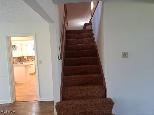 stairway with wood finished floors and baseboards