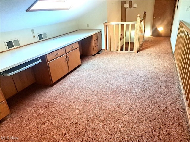 additional living space featuring visible vents, built in desk, and light carpet