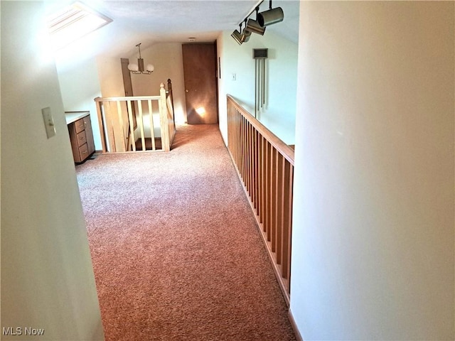 hall featuring carpet, lofted ceiling, an upstairs landing, and an inviting chandelier