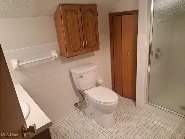 bathroom featuring a textured ceiling, tile walls, a shower stall, and toilet