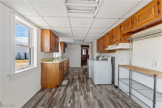 clothes washing area featuring dark wood-type flooring, independent washer and dryer, a sink, cabinet space, and baseboards