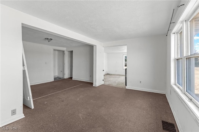 spare room with visible vents, a textured ceiling, baseboards, and carpet floors