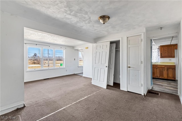 unfurnished bedroom with baseboards, a textured ceiling, and carpet flooring