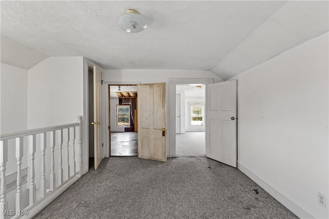 interior space featuring baseboards, a textured ceiling, and lofted ceiling