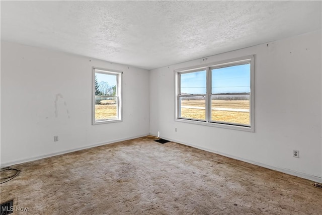 carpeted empty room featuring a textured ceiling and baseboards