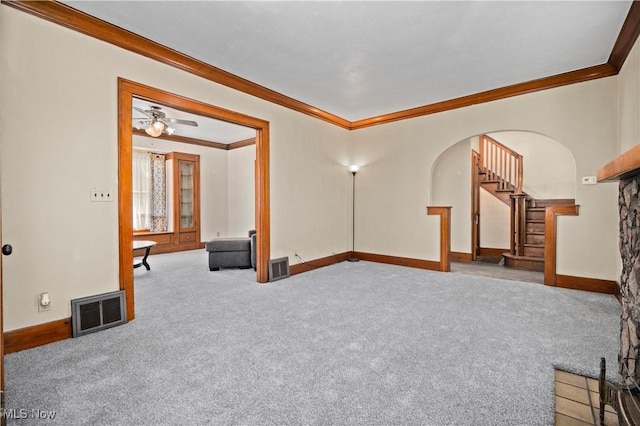 unfurnished living room featuring visible vents, carpet floors, arched walkways, and crown molding