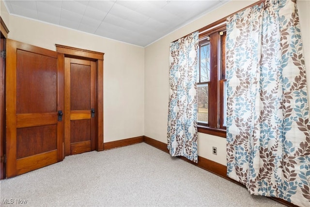 carpeted spare room with crown molding and baseboards