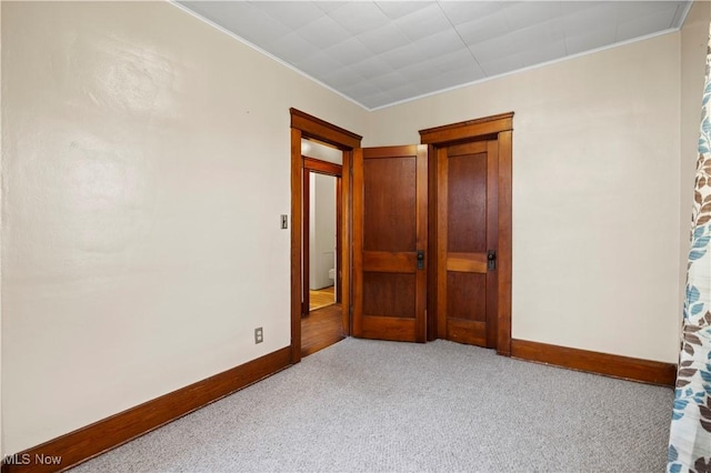 unfurnished bedroom featuring crown molding, carpet flooring, and baseboards