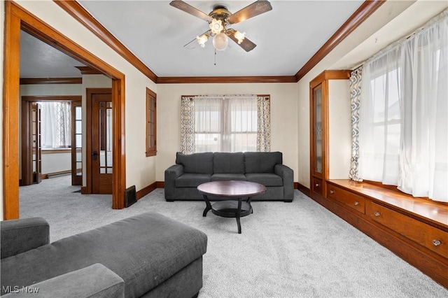 living area with a ceiling fan, plenty of natural light, carpet, and ornamental molding