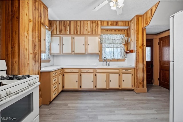 kitchen with ceiling fan, light countertops, light wood-style floors, white appliances, and a sink