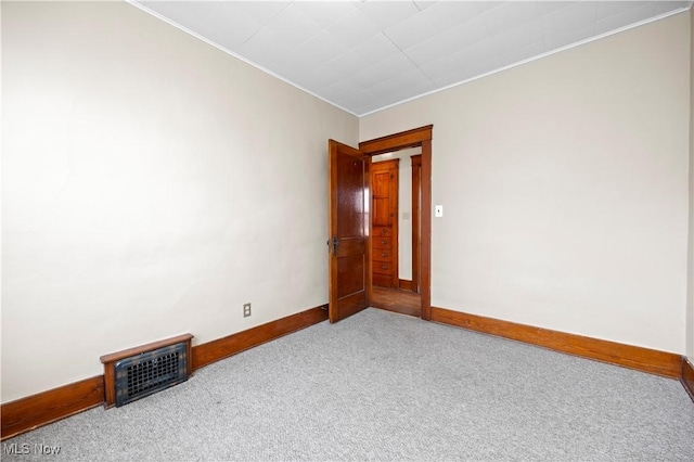 carpeted spare room with crown molding, visible vents, and baseboards