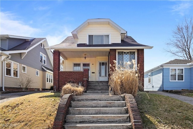 bungalow-style home featuring brick siding, a porch, and a front lawn