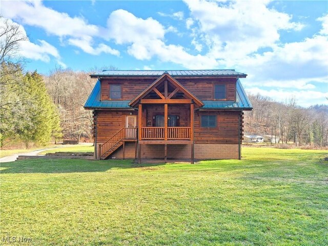 back of property with a porch, log exterior, a lawn, and metal roof