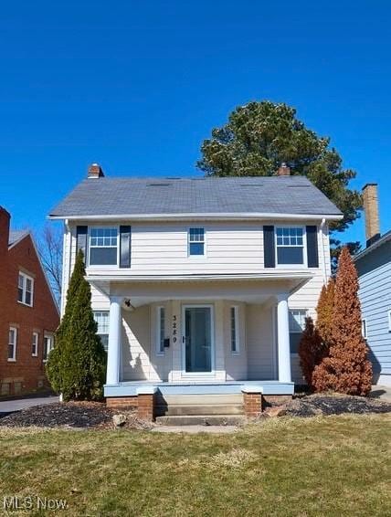 view of front of house with a porch, a chimney, and a front yard