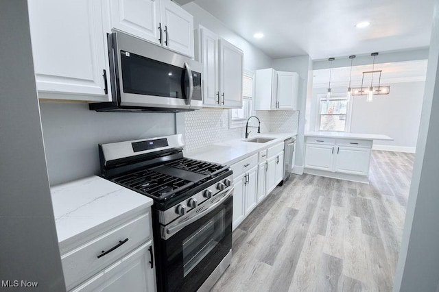 kitchen with a sink, light wood-type flooring, appliances with stainless steel finishes, and white cabinets