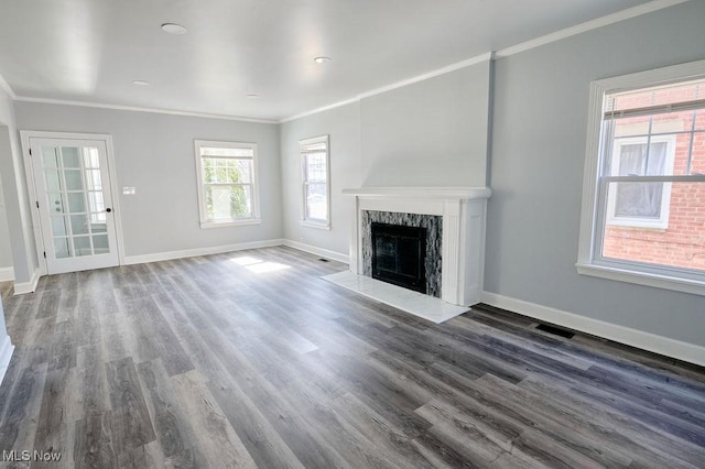 unfurnished living room with wood finished floors, baseboards, and ornamental molding