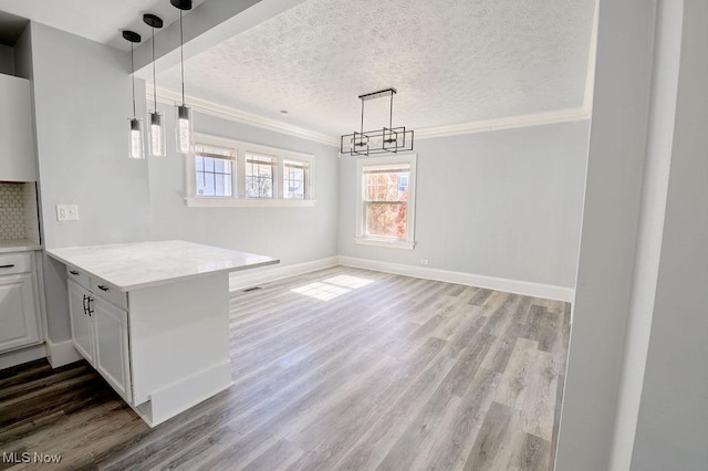 unfurnished dining area featuring an inviting chandelier, crown molding, light wood-style flooring, and a textured ceiling