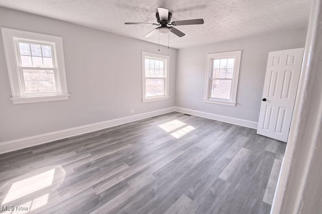 spare room featuring a textured ceiling, a ceiling fan, baseboards, and dark wood-style flooring