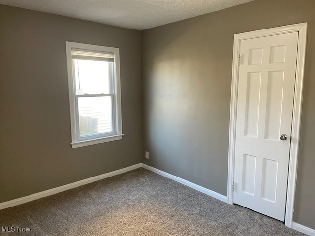 unfurnished room with baseboards, carpet, and a textured ceiling