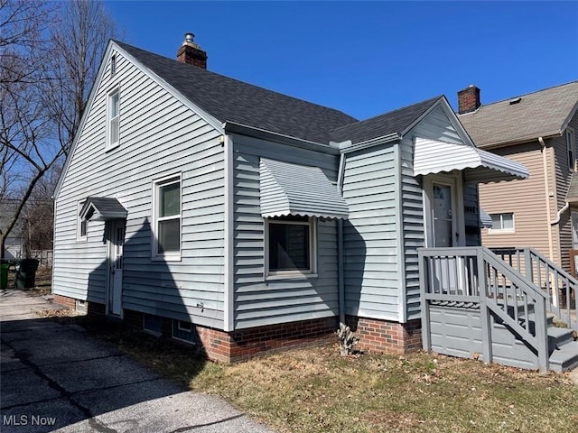 view of side of home featuring a shingled roof and a chimney