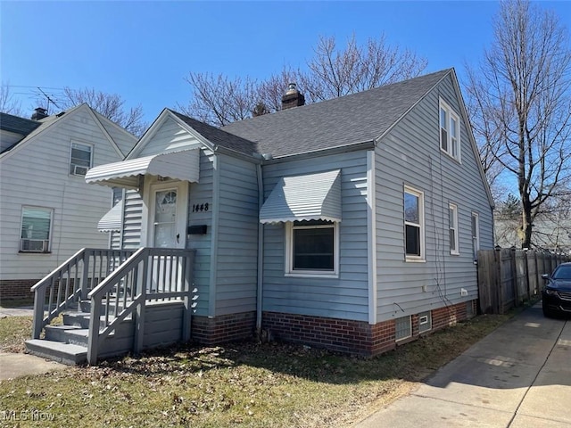 view of front of house with a shingled roof, fence, and a chimney