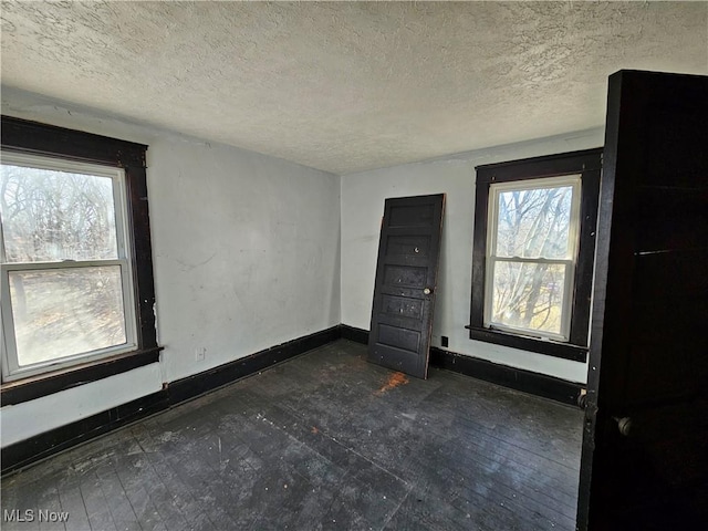 unfurnished room featuring a textured ceiling and baseboards