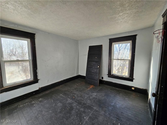 empty room featuring a textured ceiling and baseboards