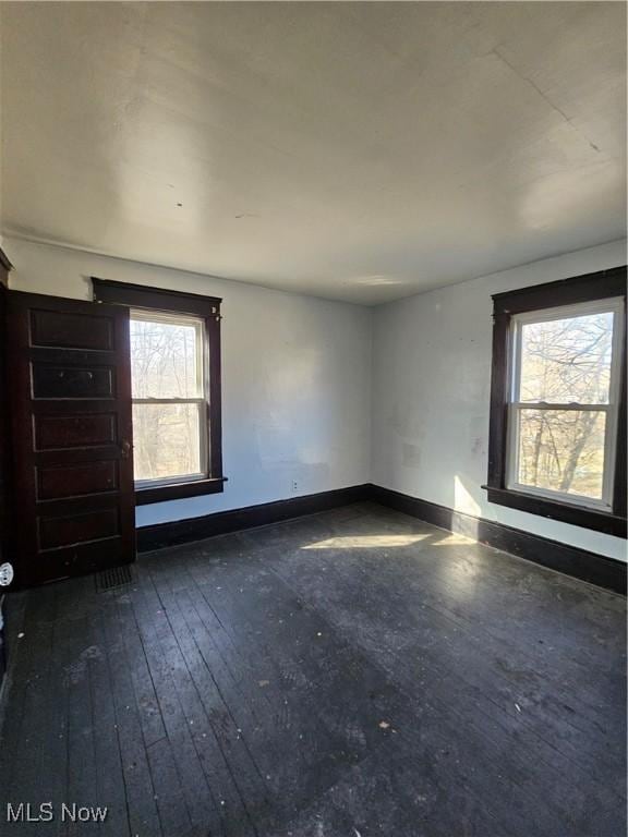 spare room with dark wood-type flooring and baseboards