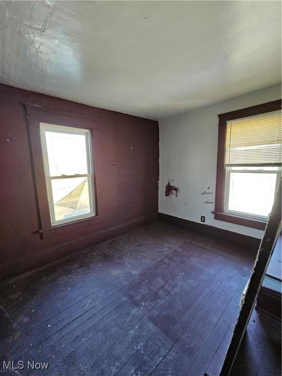 empty room featuring baseboards and dark wood-style flooring