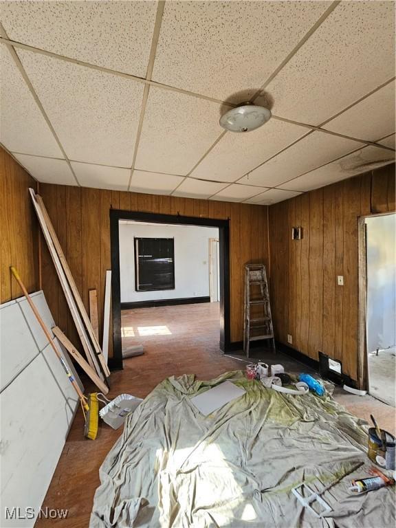 unfurnished bedroom with wooden walls and a paneled ceiling