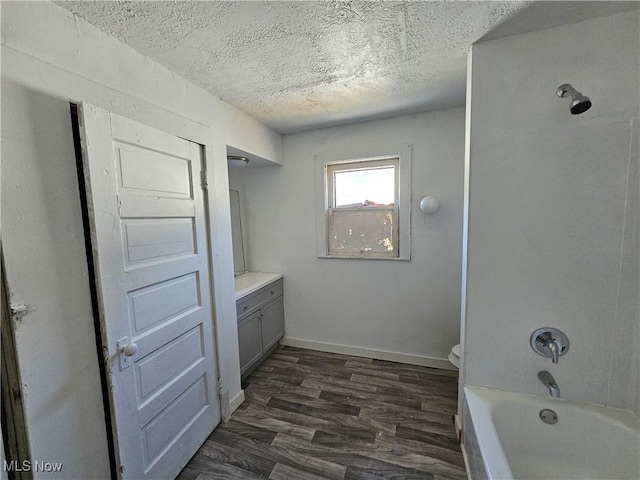 full bathroom featuring toilet, a textured ceiling, wood finished floors, baseboards, and vanity