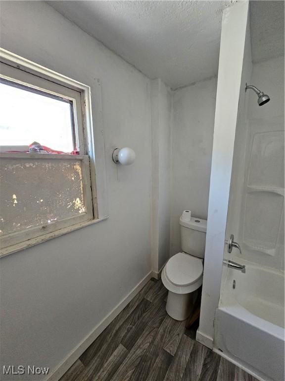 full bath featuring baseboards, toilet, shower / bathing tub combination, wood finished floors, and a textured ceiling