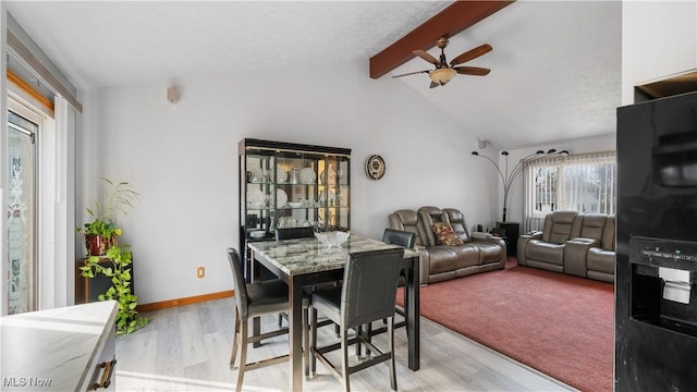 dining space with baseboards, ceiling fan, vaulted ceiling with beams, and light wood finished floors