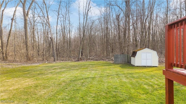 view of yard with an outdoor structure, a storage unit, and a wooded view