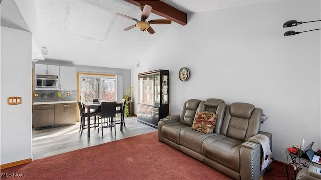 living room with baseboards, ceiling fan, beamed ceiling, light colored carpet, and high vaulted ceiling