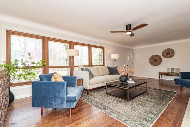 living area featuring plenty of natural light, wood finished floors, baseboards, and ceiling fan