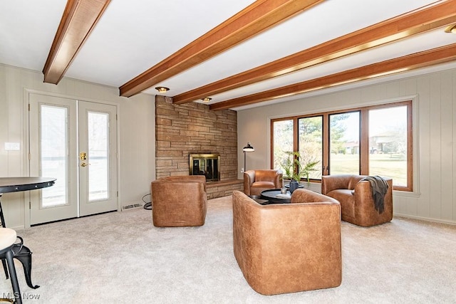 living area with french doors, beam ceiling, carpet, and a stone fireplace