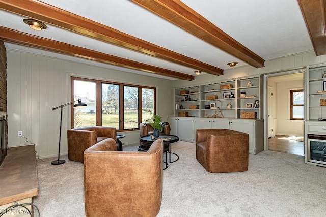 living room featuring beam ceiling, wooden walls, plenty of natural light, and carpet