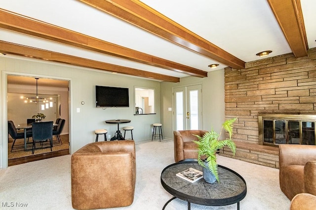 carpeted living area with an inviting chandelier, beam ceiling, and a fireplace