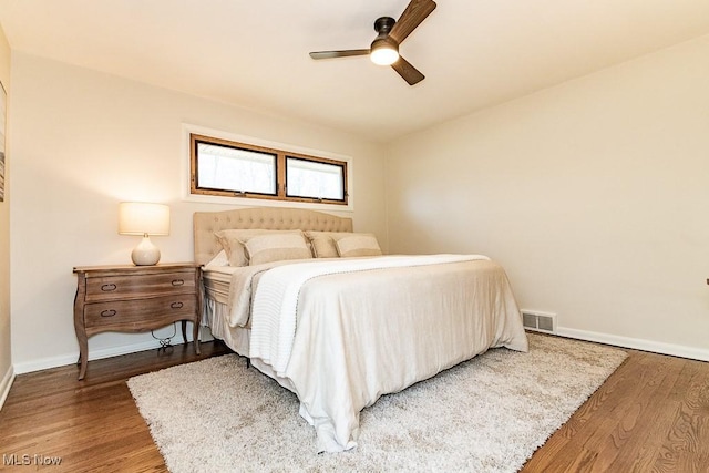 bedroom featuring a ceiling fan, wood finished floors, visible vents, and baseboards