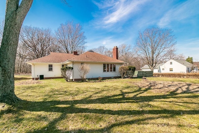 rear view of house with a yard, a garage, and a chimney