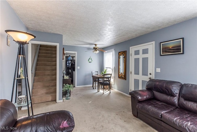 carpeted living area with stairway, a ceiling fan, baseboards, and a textured ceiling