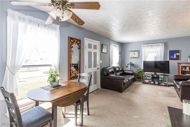 dining area featuring light colored carpet, a ceiling fan, and a textured ceiling