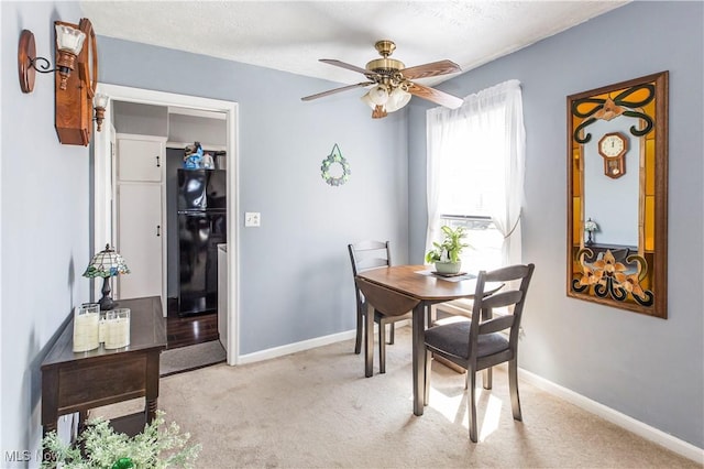 dining room featuring light colored carpet, a textured ceiling, baseboards, and ceiling fan