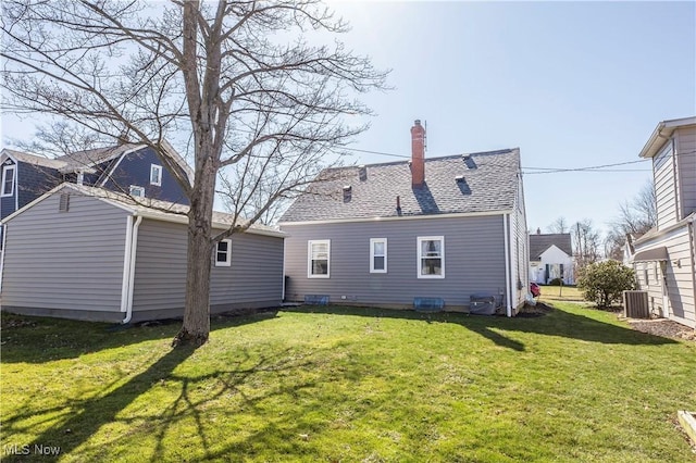 rear view of property featuring a yard, central AC, and a chimney