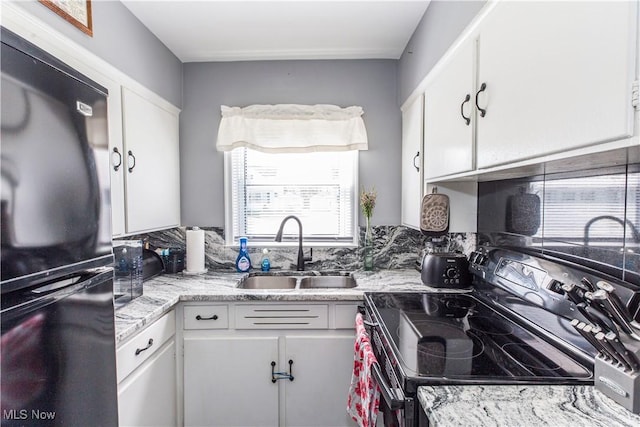 kitchen featuring a sink, range with electric cooktop, white cabinets, and freestanding refrigerator